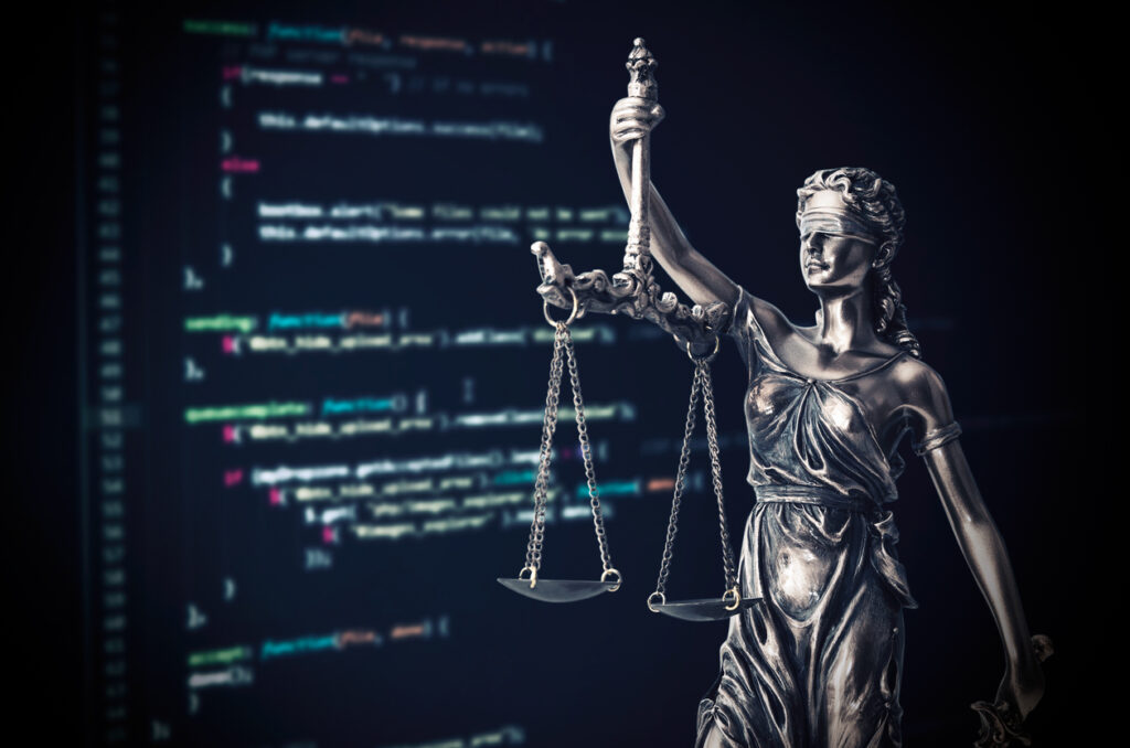 Statue Justitia vor einem Bildschirm mit Programmiercode, ein Sinnbild für die Digitalisierung der Rechtsbranche